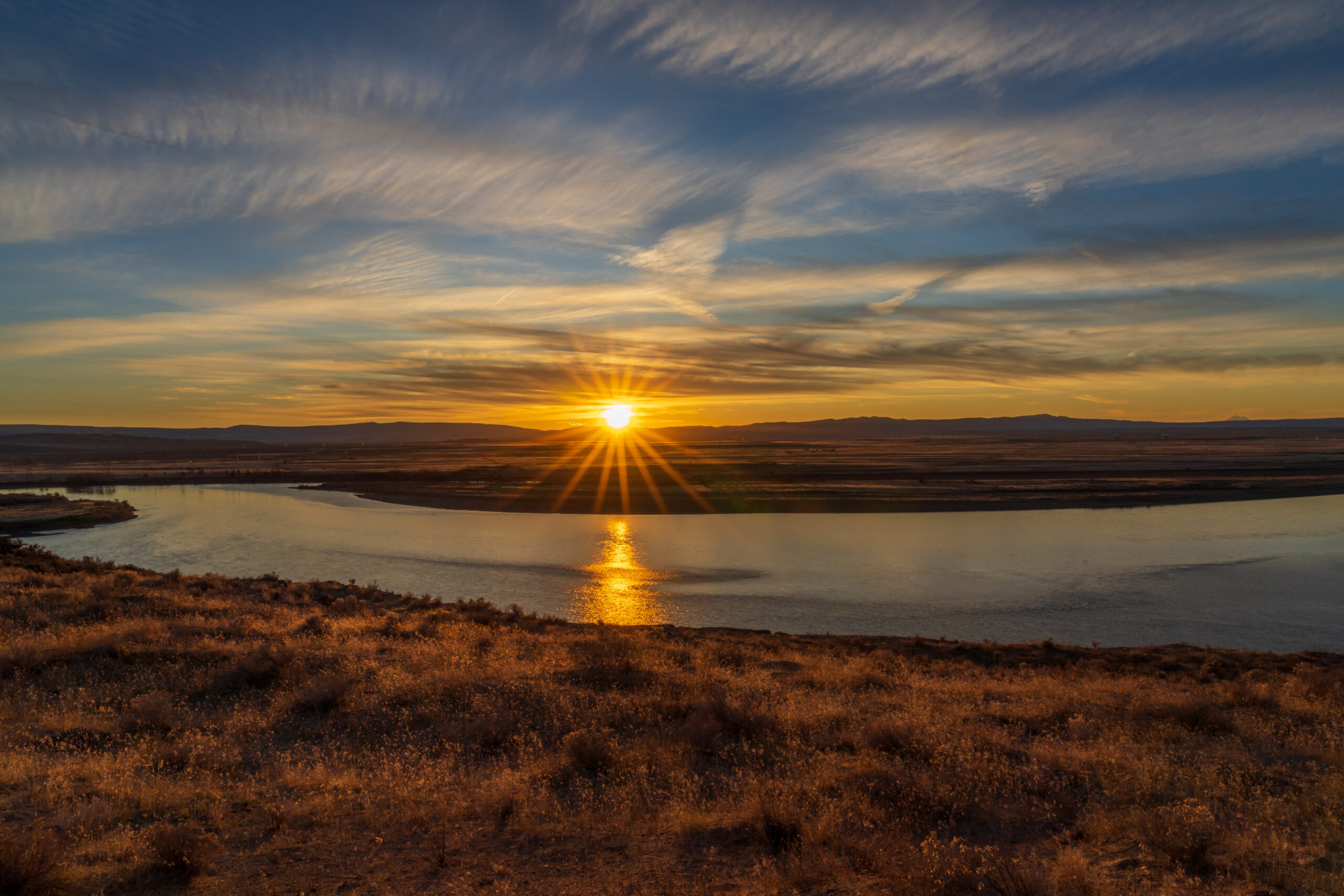 Sunset over river with golden reflection and hills